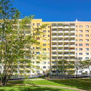 Saniertes, mehrfarbiges Hochhaus in Potsdam West hinter grünen Bäumen